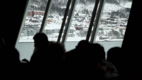 View-of-a-snowy-village-from-inside-a-moving-ship-with-people-against-the-light