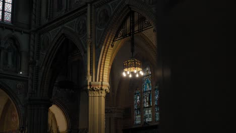 Aufschlussreiche-Aufnahme-In-Einer-Schwach-Beleuchteten-Kirche-Mit-Buntglasfenstern-Und-Torbögen