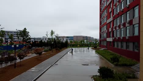 Dos-Trabajadores-Chinos-Barriendo-El-Pavimento-Después-De-La-Lluvia---Campus-Weihai-De-La-Universidad-Jiaotong-De-Beijing,-China
