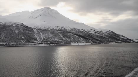 Hermosa-Vista-De-Una-Montaña-Cubierta-De-Nieve-Desde-Un-Barco-En-Movimiento-En-El-Mar-Noruego