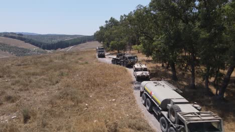 Israel-Army-squad-soldier's-vehicles-standing-in-queue-in-narrow-road,-Aerial-Tracking-shot