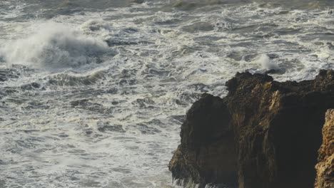 Rough-stormy-sea-and-cliffs-on-Nazare-Portugal-coast,-power-of-nature,-stable-bad-weather-view