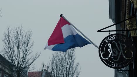 Statische-Aufnahme-Einer-Holländischen-Flagge,-Die-Vor-Einem-Café-In-Rotterdam-Im-Wind-Weht
