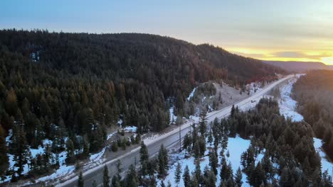 An-Aerial-Pan-of-Cars-driving-on-Cariboo-Highway-97-During-a-Winter-Sunrise-in-British-Columbia,-Canada