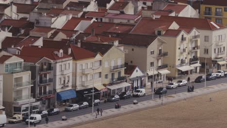 Street-along-Nazare-beach-in-Portugal,-long-telephoto-view-of-houses-and-everyday-life