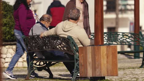 Local-people-sitting-bench-in-Nazare-street,-Portugal,-talking-together