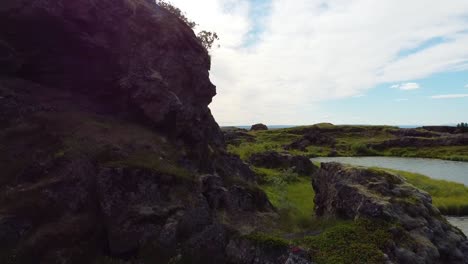 Aufsteigende-Luftaufnahme-über-Felsigem-Hügel-Mit-Schöner-Isländischer-Flusslandschaft-Und-Ozean-Im-Hintergrund