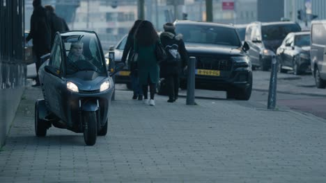 Tracking-shot-of-a-woman-driving-a-small-electric-tricycle-in-downtown-Rotterdam