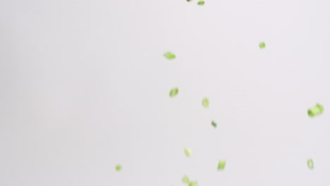 Gewürfelte-Und-Gehackte-Grüne-Zwiebelstücke,-Die-In-Zeitlupe-Auf-Weißen-Hintergrund-Regnen