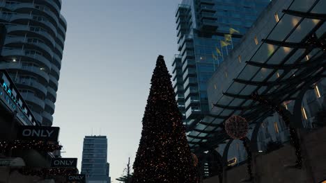 Toma-Panorámica-Hacia-Abajo-Del-árbol-De-Navidad-Decorado-En-El-Centro-De-Rotterdam-Por-La-Noche