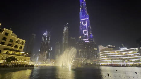 Espectáculo-De-Agua-De-La-Fuente-De-Dubai-Visto-En-Una-Amplia-Escena-Cerca-Del-Espectáculo-De-Luces-Burj-Khalifa