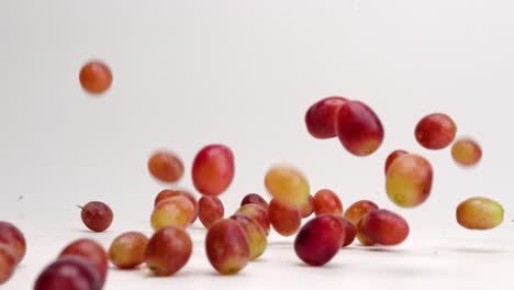 Fresh-red-grapes-off-the-vine-falling-and-bouncing-and-rolling-around-on-white-table-top-in-slow-motion