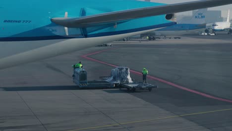 Static-shot-of-airport-workers-transferring-luggage-across-machines-on-the-runway
