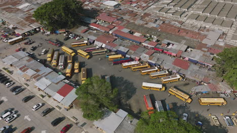 Rotating-aerial-footage-of-a-bus-station-in-the-market-in-Antigua,-Guatemala