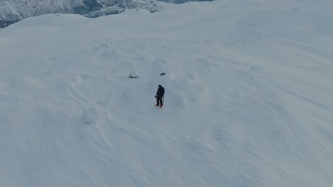 Esquiador-Solo-En-La-Cima-De-La-Cumbre-Finnbunuten-En-El-Paisaje-Cubierto-De-Nieve-Myrkdalen-Noruega---Antena-Girando-Sobre-El-Hombre-Mientras-Cambia-La-Altitud-Y-El-Fondo