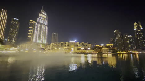Smoke-on-the-water-in-the-Dubai-fountain-seen-at-night-with-luxurious-restaurants-in-the-background