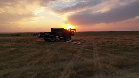 Cinematic-sunset-aerial-toward-HORSCH-autonomous-sprayer-tractor-on-farm-land