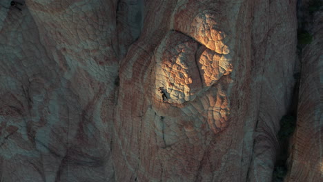 Luftaufnahme-Von-Oben-Nach-Unten,-Frau,-Die-Auf-Erstaunlichen-Hügeligen-Sandsteinformationen-Liegt