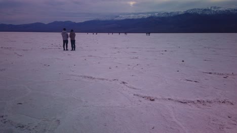 Gimbal-tilting-up-shot-of-tourists-standing-in-the-salt-flats-of-Badwater-Basin-in-Death-Valley,-California