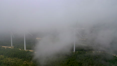 Luftaufnahme-Bei-Nebel-Von-Drehenden-Windkraftanlagen-Auf-Dem-Bergrücken