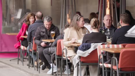 People-enjoy-drinks-and-meals-in-street-restaurant-of-Barcelona,-handheld