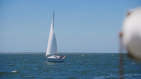 Ein-Weißes-Segelboot,-Das-Auf-Dem-Offenen-Meer-Mit-Einer-Holländischen-Flagge-In-Zeitlupe-Segelt