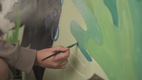 Close-up-hand-with-brush-painting-mural-on-the-wall,slow-motion