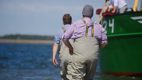 Hard-working-fisherman's-walking-in-the-sea-towards-a-boat-in-slowmotion