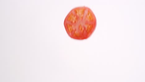 Fresh-red-tomato-slices-raining-down-in-slow-motion-on-white-backdrop-in-slow-motion