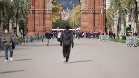 Powerful-blurred-man-walk-towards-Arc-de-Triomf-in-Barcelona,-back-slow-motion-view