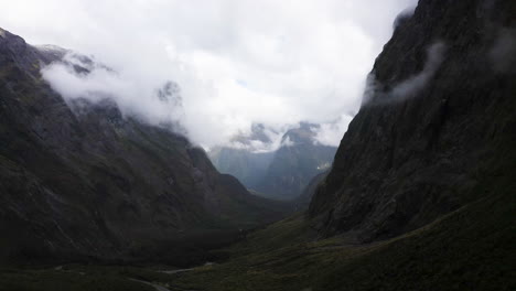Winding-road-passing-thru-the-mountains,-fog,-and-clouds-in-Milford-Sound-New-Zealand-on-the-South-Island