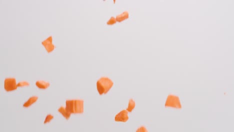 Gewürfelte-Orangefarbene-Süßkartoffeln,-Die-In-Zeitlupe-Auf-Weißen-Hintergrund-Regnen