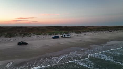 Vehicle-Driving-Through-The-Sandy-Shore-Of-The-Beach-In-Padre-Island,Texas,USA---aerial-drone-shot