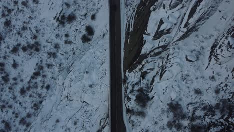 Topdown-view-along-empty-Mountain-road,-covered-in-snow-landscape