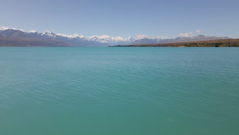 Soaring-low-over-the-tranquil-lake-Pukaki-in-New-Zealand,-towards-Mt-Cook-and-the-Southern-Alps