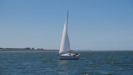 A-white-sailboat-sailing-on-the-sea-on-a-summer-day-in-the-afternoon-in-slowmotion