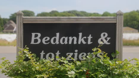 A-welcome-and-goodbye-sign-in-Dutch-of-a-company-with-green-bushes-around-it