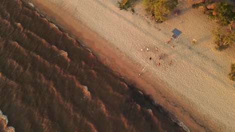 Aerial-top-down-shot-of-people-playing-volleyball-at-sandy-beach-during-sunset