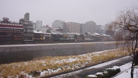 Snow-falling-over-Kyoto-City-along-the-Kamo-River,-Winter-in-Japan
