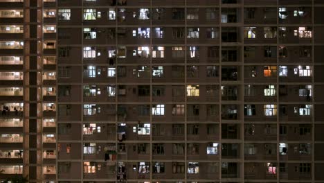 Una-Vista-Nocturna-De-Un-Edificio-De-Viviendas-Públicas-De-Gran-Altura-Lleno-De-Gente-En-Hong-Kong