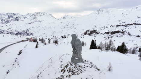 Eagle-sculpture-of-stone-overlooking-the-Simplon-pass-with-in-the-background-the-high-Swiss-alps-covered-by-snow