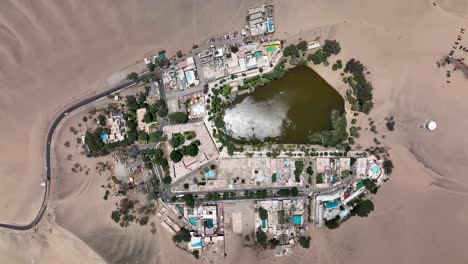 Desert-oasis-Huacachina,-Peru-with-lake-and-palms,-with-great-sand-dunes-in-the-background