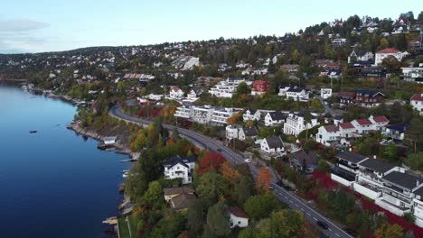 aerial-view-of-katten-beach-houses-near-oslo,-you-can-see-the-norwegian-colored-houses-and-cars-driving-on-the-road-near-the-beach