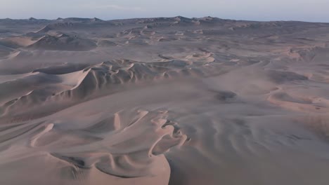 Aerial-view-of-a-drone-flying-over-desert-massive-sand-dunes-at-sunrise