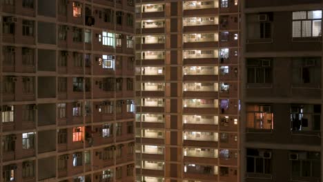 Una-Vista-Nocturna-De-Un-Edificio-De-Viviendas-Públicas-De-Gran-Altura-Lleno-De-Gente-En-Hong-Kong