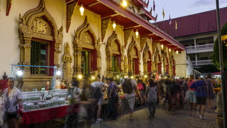 Time-lapse-of-people-shopping-at-night-market-outside-ornate-Chiang-Mai-temple