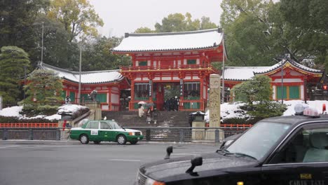 Winter-in-Kyoto-Japan,-Cars-Drive-Through-Gion-and-Yasaka-Jinja-on-Snowy-Day