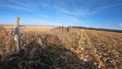point-of-view---driving-UTV-along-a-barbed-wire-fence-between-two-harvested-corn-fields