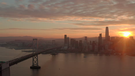Luftschieberaufnahme-Der-Skyline-Von-San-Francisco-Und-Der-Bay-Bridge-Bei-Sonnenuntergang