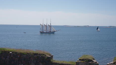 Vintage-wooden-tall-ship-sailing-across-calm-blue-ocean-horizon
